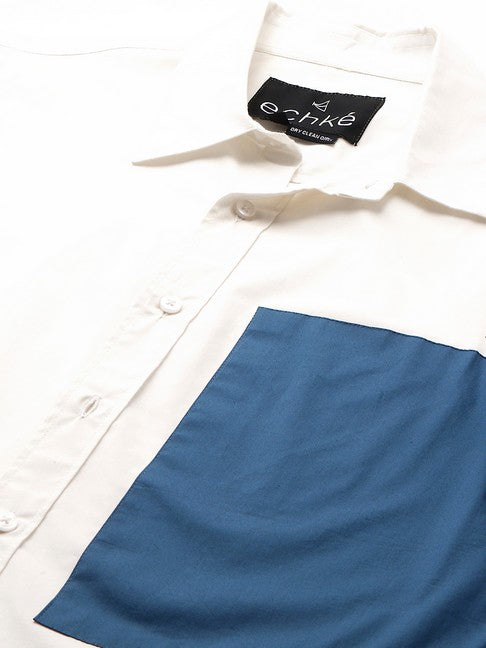 White shirt with slate blue patch on left sleeve and chest with button detailing